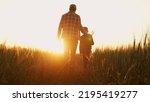 Small photo of Farmer and his son in front of a sunset agricultural landscape. Man and a boy in a countryside field. Fatherhood, country life, farming and country lifestyle.