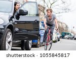 Small photo of Angry young bicyclist shouting while swerving for avoiding dangerous collision with the open door of a 4x4 car on a busy street in the city