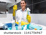 Small photo of Janitor woman or charlady with her work tools looking at camera in toilet