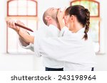 Man and woman fighting with wooden knifes at Aikido training in martial arts school 