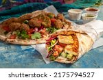 Small photo of Traditional Mediterranean Arabic grilled halloumi and falafel, hummus and vegetables in flatbread wraps with herbs and a variety of sauces