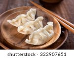Close up fresh boiled dumplings with hot steams on wood plate. Chinese food on rustic old vintage wooden background. 