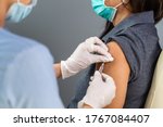 Small photo of close up doctor holding syringe and using cotton before make injection to patient in medical mask. Covid-19 or coronavirus vaccine