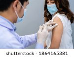 Small photo of doctor holding syringe and using cotton before make injection to patient in a medical mask. Covid-19 or coronavirus vaccine