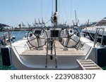 Small photo of White sailing yacht on the quay in the port on a cloudy day, view from the stern. High-quality photo. boat stern with big steering wheel and sailboat stern deck. Close-up