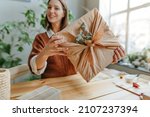 Young woman holding gift box packing in fabric furoshiki style with dried eucalyptus. Eco friendly package concept. Selective focus.
