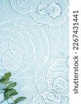 Small photo of Blue water texture, surface with rings and ripples. Green leaves on water surface. Spa concept background. Flat lay, copy space.