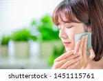 Small photo of Young asian skin care woman smile and use oil blotting paper on her face