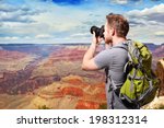 Young man with backpack taking a photo on the top of mountains at Grand Canyon, caucasian