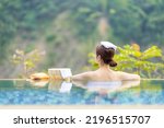 back view of asian woman sitting in hot spring pool relaxing
