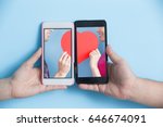 Small photo of hand take smart phone with young couple take heart in screen on blue background