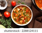 Small photo of Vegetable cabbage soup in bowl over wooden background. Top view, flat lay