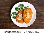 Chicken schnitzel on plate over wooden background. Top view, flat lay
