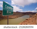 A green road sign indicating the Colorado River crossing below the bridge in Utah