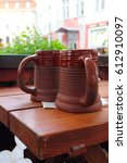 Small photo of Two traditional clay beeg mugs on wooden table in cafe