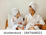 happy family mother and little daughter in bathrobe and towels est and relax with a Cup of coffee in bed at home
