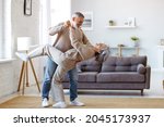 Keep moving. Romantic senior family couple wife and husband dancing to music together in living room, smiling laughing retired man and woman having fun, enjoying free time together at home