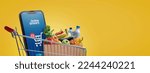 Small photo of Supermarket shopping cart full of groceries and smartphone with online grocery shopping app, copy space