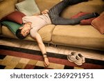 Photo of a young and handsome man resting in a strange position on the floor with a pillow under his head, maybe drunk or very tired