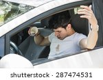 Young Man Having a Bad Day, Distracted Driver Looking Down in Frustration at Spilled Coffee on White T-Shirt While Sitting in Drivers Seat of Car