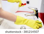 Female hands with rubber gloves spraying liquid detergent on tap and cleaning it with sponge. Spring cleaning