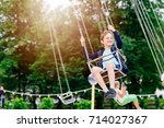 Happy child boy having fun in amusement park. Taking a ride on chain carousel.