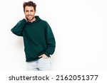 Handsome smiling hipster  model.Sexy unshaven man dressed in summer stylish green hoodie clothes. Fashion male with curly hairstyle posing in studio. Isolated on white