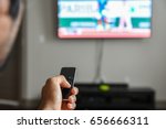 Man using remote control to switch channels. Close up hand holding apple tv remote