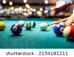 female hand collects colored balls after playing billiards and prepares a new game. Concept of spending free time with games