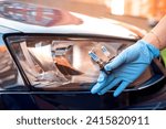 Small photo of mechanic with hardworking hands holding halogen lamp near car headlight. car repair by a locksmith. replacing a halogen lamp