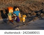Small photo of NITRA, SK - JANUARY 8, 2024: LEGO Minecraft Alex with iron pickaxe, smiling Steve and pet friend Ocelot on a walk across icy surface in winter morning sunshine.