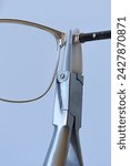 Small photo of Adjusting inclination of temples on modern metal eyeglass frame with conical inclination pliers equipped with nylon replaceable jaws.