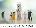 Small photo of Wooden blocks with the word VAT with miniature people. Value-added tax (VAT) is a flat tax levied on an item. It is similar to a sales tax in some respects, except that with a sales tax.