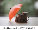 Umbrella on stacks and heaps of coins, nature background. Coverage, insurance or protection concept. Money saving or money investment protection
