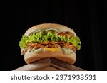 perfect tasty big chicken cheeseburger on wooden table on brown background