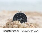 Small photo of Classic navigation compass on beach against blue sea as symbol of tourism with compass, travel with compass and outdoor activities with compass