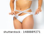 Close up female waist in white bikini. Hands measuring waist with metric band.