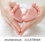 newborn baby feet on female hands, shape like a lovely heart