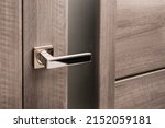 Close up of stylish silver chrome door handle on modern interior door. Stylish light brown door with frosted glass inserts. Concept of catalog of door handles for furniture store.