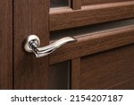 Small photo of External door handle without protective lock on wooden frame. Close up of metallic door handle on brown front or interior door. Home door design choice concept.