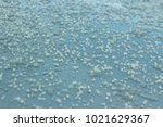 Frozen hailstones on a silver car roof following a cold winter shower 
