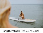 Small photo of Two pretty young women in the sea with addle board on a summer day