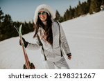 Young woman standing with skis on the ski track at a sunny day