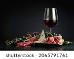 Small photo of Red wine with grapes, rosemary, prosciutto, and blue cheese on a dark background.