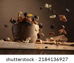 Small photo of Flying dried fruits and nuts. The mix of dried nuts and raisins on an old wooden table. Selective focus.