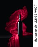Small photo of Bottle of red wine on a black background with flutters red cloth. Copy space.