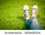 youth sneakers on girl legs on grass during sunny serene summer day.