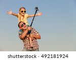 Dad and daughter in sunglasses playing near a house at the day time. People having fun outdoors.  Concept of friendly family.