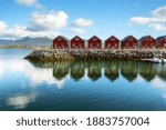 Traditional red wooden houses on the shore of Offersoystraumen fjord. Fantastic summer sunset on Vestvagoy island. Picturesque evening view of Lofoten Islands, Norway, Europe. Life over polar circle