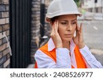 Small photo of Tired construction manager suffering from temporal headache on development site